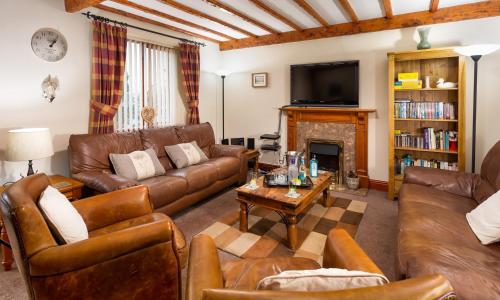 a living room with leather furniture and a fireplace at Thomas Fold Cottage in Ambleside