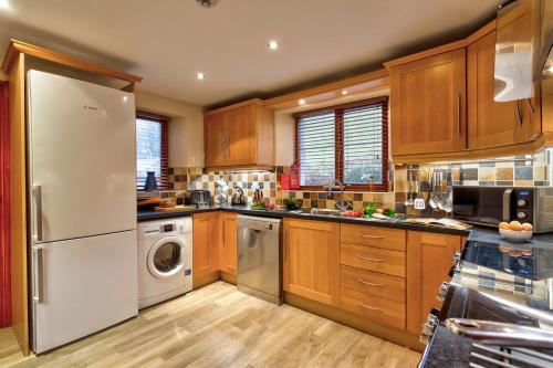 a kitchen with wooden cabinets and a white refrigerator at Thomas Fold Cottage in Ambleside