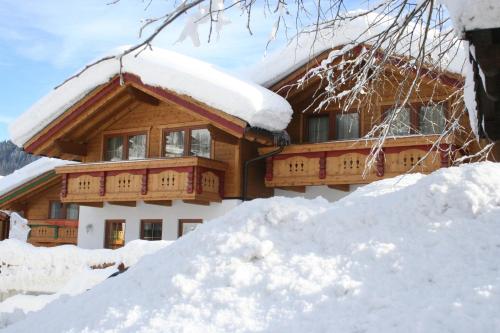 a house covered in snow next to a pile of snow at Feriendorf Wildschönau in Niederau