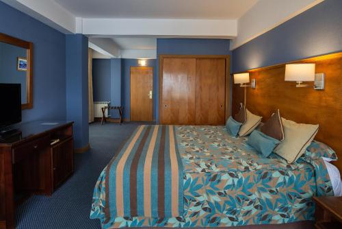 a hotel room with a bed and a television at Hotel Tierra del Fuego in Ushuaia