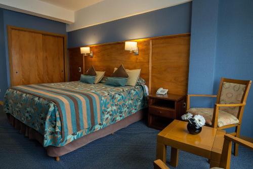 a hotel room with a bed and a chair at Hotel Tierra del Fuego in Ushuaia