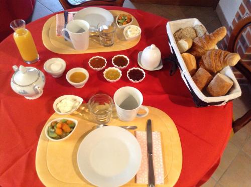 a red table topped with plates of food and bread at Chambre d'hôte du HOUSSAY à VALENNES 72320 in Valennes