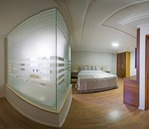 Laguna Plaza Hotel في برازيليا: غرفة نوم بسرير وجدار زجاجي