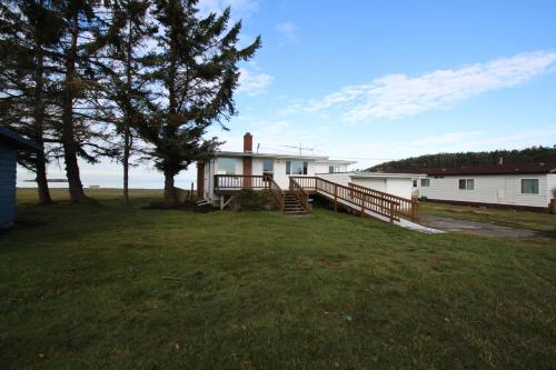 a white house with a porch and a tree at Lopez Island Agate Beach Waterfront Home in Islandale