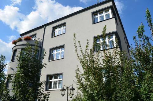 een wit gebouw met ramen en een boom bij Hostel Gwarek in Katowice