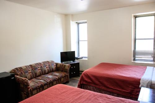 a hotel room with a couch and a bed and a tv at Hotel Casa Bella in Montréal