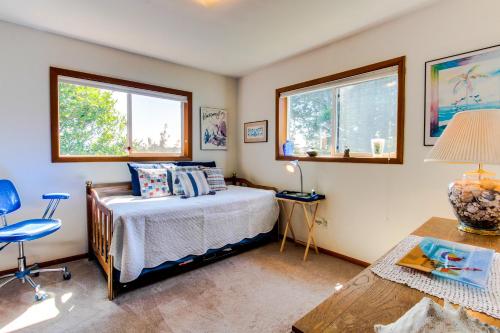 a bedroom with a bed and a table and two windows at Nye Beach Bungalow in Newport