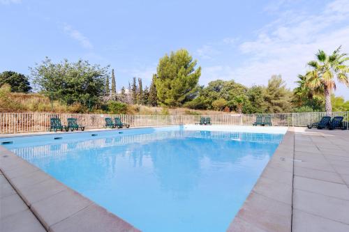 une grande piscine bleue avec des chaises et une clôture dans l'établissement Comfort Aparthotel Six-Fours, à Six-Fours-les-Plages