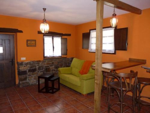 a living room with a green couch and a table at Casa AL ABLUGO in Pola de Somiedo