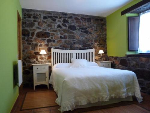 a bedroom with a large bed and a stone wall at Casa AL ABLUGO in Pola de Somiedo