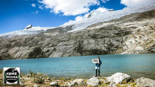 a man holding a sign in front of a mountain at Kame House hostel in Huaraz