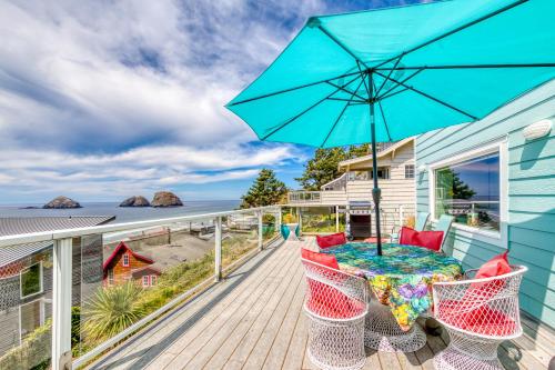 a blue house with a deck with a table and an umbrella at Hale Kaalawai in Oceanside