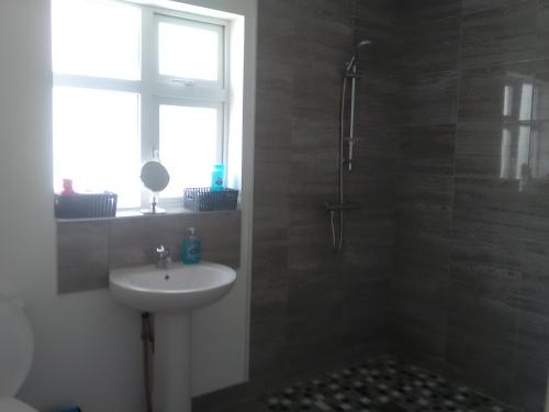 a bathroom with a sink and a shower with a window at Casa Tara in Lahinch