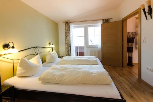 1 dormitorio con 2 camas con sábanas y almohadas blancas en Vicky Apartments, en Niederau