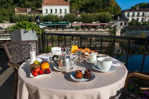 a table with food and fruit on a balcony at Hotel Restaurant Charbonnel in Brantôme