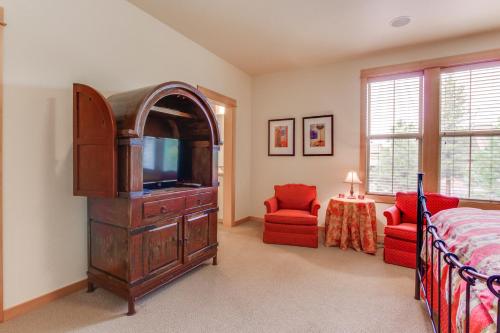 a bedroom with a tv and a bed and two red chairs at 23 Fremont Crossing Sunriver in Sunriver