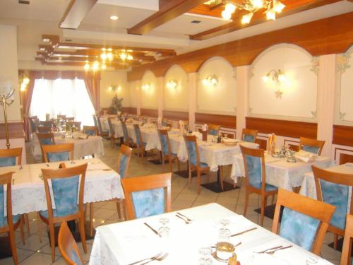 un comedor con mesas y sillas blancas en Miramonti Hotel, en Garniga Terme