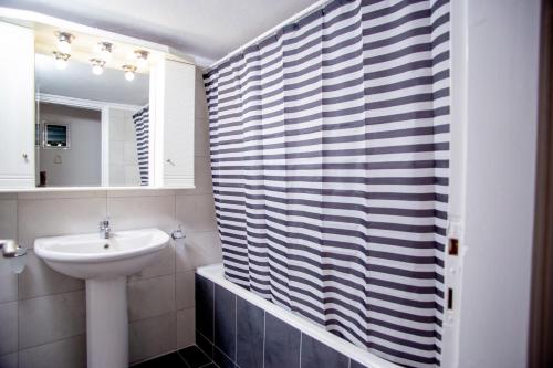 a bathroom with a sink and a shower curtain at Thessaloniki Center Apartment On The Sea in Thessaloniki