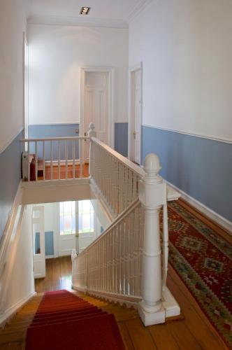 a white staircase in a home with a red rug at Zerohotel in Valparaíso