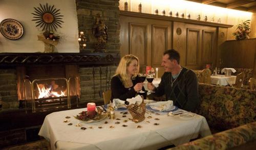 a man and woman sitting at a table with wine glasses at Hotel Metzgerwirt in Fieberbrunn