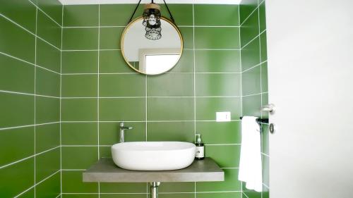 a green tiled bathroom with a sink and a mirror at Il nido dei gufi in San Maurizio Canavese