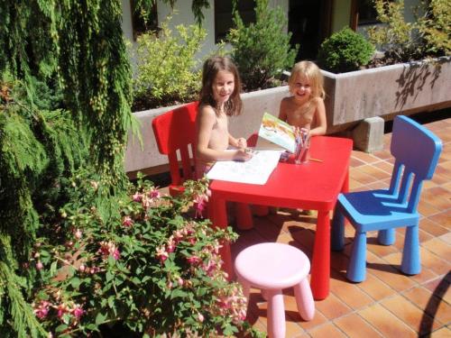 two little girls sitting at a table reading a book at Hotel Metzgerwirt in Fieberbrunn
