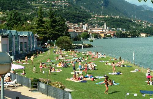 a group of people sitting on the grass near the water at Casa Tiziana in Sovere