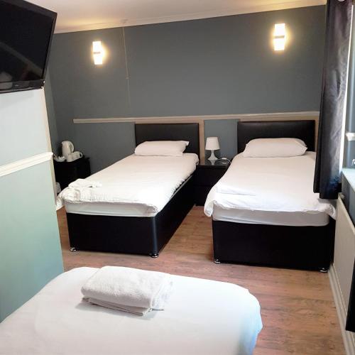 two beds in a small room with white sheets at The Dorchester Hotel & serviced apartments in Hull