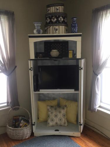 a shelf with a television in a room with windows at Glass Magnolia Bed & Breakfast in Interlaken