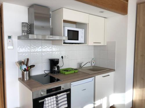 une cuisine blanche avec un évier et un micro-ondes dans l'établissement Résidence Porto Marine, à Porto Ota