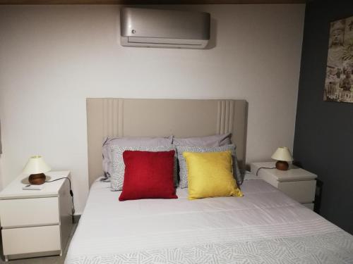 um quarto com uma cama branca e 3 almofadas coloridas em Casa da Esperança na Lourinhã