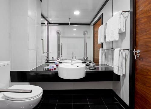 a white bathroom with a sink and a toilet at Leonardo Royal London Tower Bridge in London