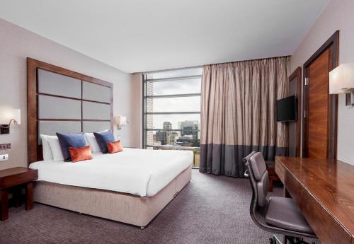 a hotel room with a large bed and a large window at Leonardo Royal London Tower Bridge in London