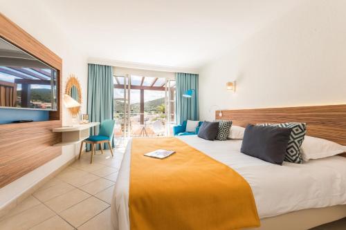 a hotel room with a large bed and a desk at Hôtel de l'Esterel Pierre & Vacances in Agay - Saint Raphael