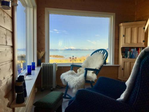 a room with two chairs and a large window at Beach View Lofoten in Bøstad