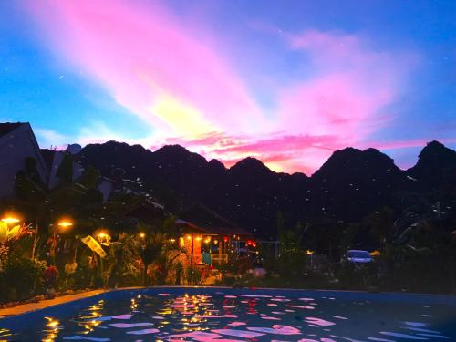 a pool with a view of the mountains at sunset at Lucky Homes in Phong Nha