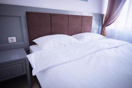 a large white bed with white sheets and pillows at HOTEL GLARIS in Tîrgu Frumos
