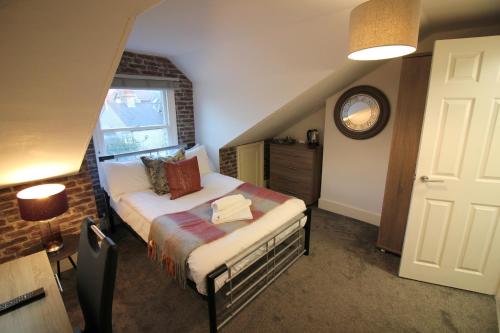 1 dormitorio con 1 cama y reloj en la pared en Cambridge City Rooms by Paymán Club, en Cambridge