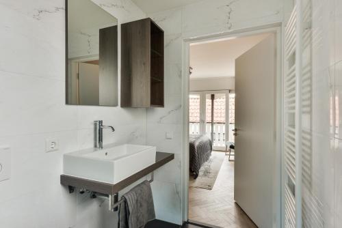 La salle de bains blanche est pourvue d'un lavabo et d'un miroir. dans l'établissement Boutique hotel The Old Bridge, Volendam, à Volendam