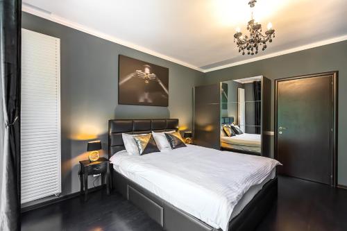 een slaapkamer met een groot bed en een kroonluchter bij Tampa Gardens Apartments - Adults Only in Braşov