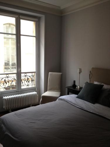une chambre avec un lit, une chaise et une fenêtre dans l'établissement Appartement Cherche-Midi, à Paris