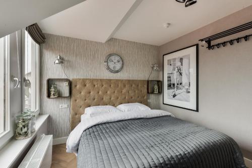 1 dormitorio con 1 cama y reloj en la pared en Boutique hotel The Old Bridge, Volendam, en Volendam