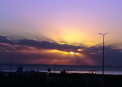 - un coucher de soleil sur l'océan avec une lumière de rue dans l'établissement Light House, à Marsa Alam