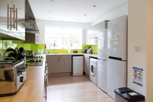 a kitchen with white appliances and green walls at Cambridge City Rooms by Paymán Club in Cambridge