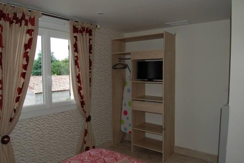 Habitación con 1 dormitorio con TV y ventana. en Gite Millesime Proche St Emillion, en Abzac