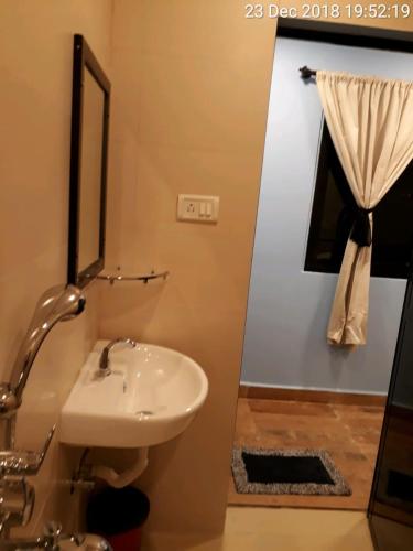 a bathroom with a white sink and a window at Boaty's Beach Cottages in Calangute