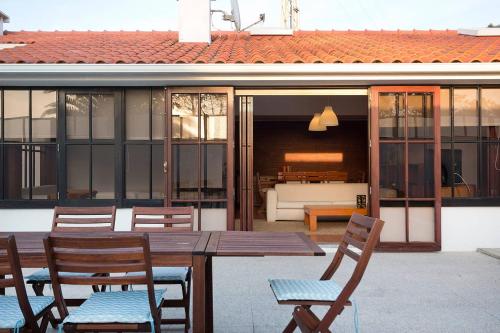 Une table et des chaises en bois sont disponibles sur la terrasse. dans l'établissement 4 bedroom Luxury Villa - riverside & beachside, à Esposende