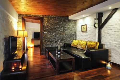 a living room with a black leather couch and a table at Apartamenty Chleb i Wino Toruń in Toruń