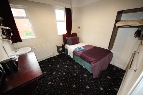 a hotel room with a bed, desk, and toilet at Avalon Guest House in Leeds