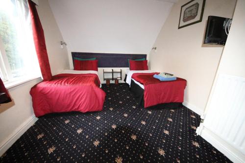 a hotel room with two beds and a red rug at Avalon Guest House in Leeds